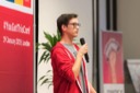 Daniel Spindelbauer from Git Hub Education, one of the conference sponsors, speaks at the You Got This conference. Daniel wears a red hoodie top over a grey t-shirt and a pair of black rectangular-rimmed glasses.