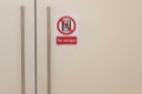 A sign on the conference room door reads, No escape. The sign features an icon of a person trying to exit through the door. The icon is surrounded by a red circle with a diagonal red line through the scene.